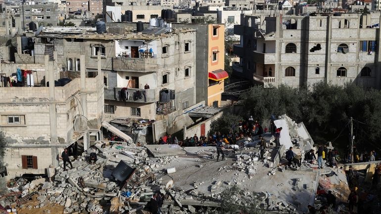 Palestinians look at the destruction after an Israeli strike on...