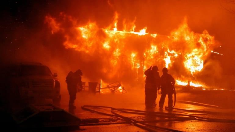Flames engulf a Selden home Wednesday night where the body...