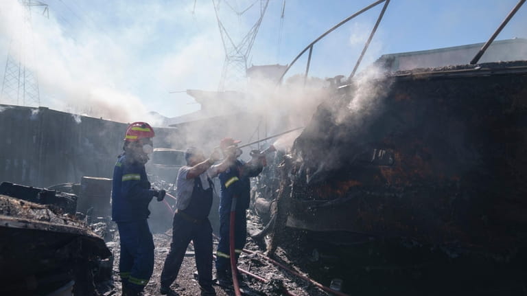 Firefighters try to extinguish a yacht on fire in Koropi...