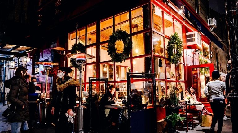 Customers sit in the outdoor dining area of a restaurant...