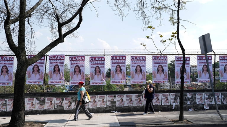 Pedestrians walk past campaign posters promoting mayoral ruling party candidate...