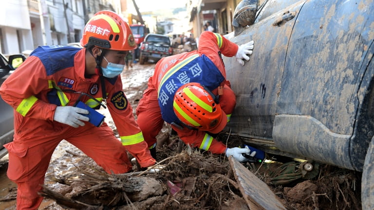 In this photo released by Xinhua News Agency, rescuers look...
