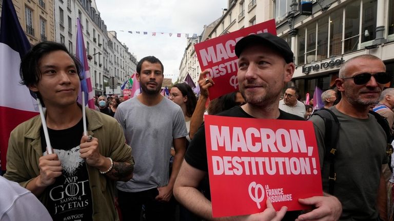 People, some carrying placards, participate in a protest demonstration responding...