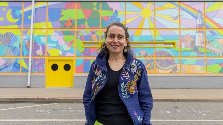 Muralist Viktoriya Basina stands in front of the new mural...