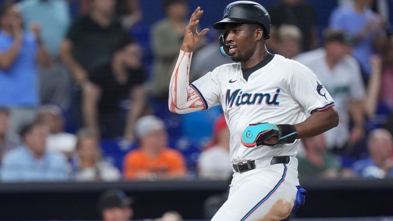 Miami Marlins' Jesús Sánchez heads for home to score on...