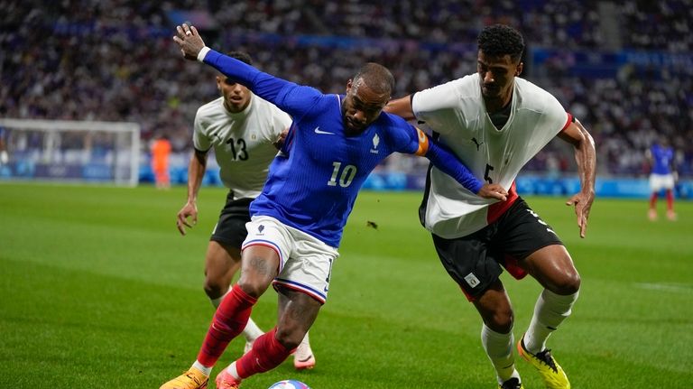 France's Alexandre Lacazette, center, and Egypt's Hossam Abdelmaguid battle for...