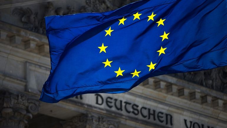 A European flag waves in front of the Reichstag building...