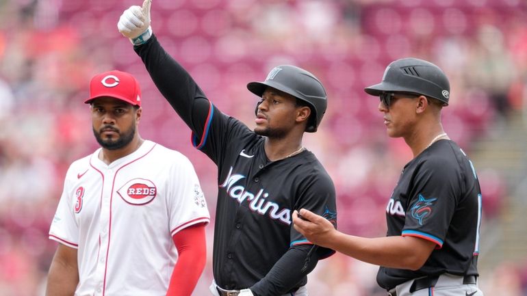 Miami Marlins' Xavier Edwards, center, gestures after hitting a single...