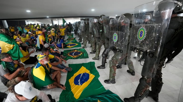 Supporters of Brazil's former President Jair Bolsonaro sit in front...