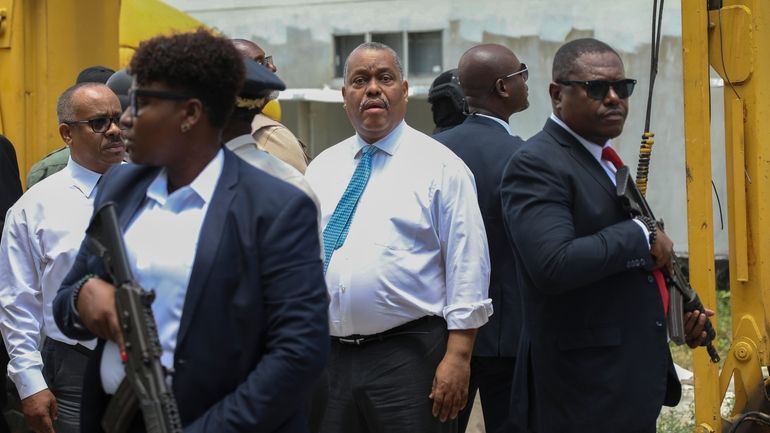 Haitian Prime Minister Garry Conille, center, is surrounded by security...