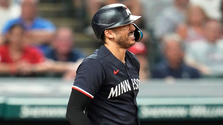 The Twins' Carlos Correa grimaces after being hit by a...