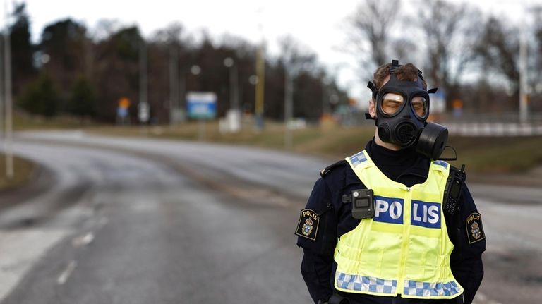 A police officer with a gas mask stands guard near...