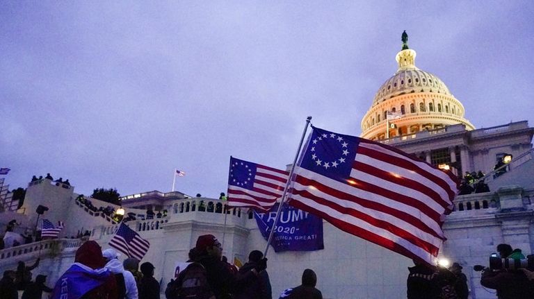 Rioters walk on the West Front of the U.S. Capitol...