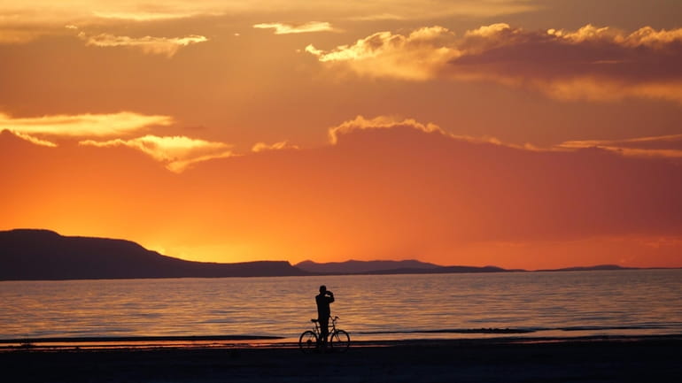 A man on a bike photographs the sunset at the...