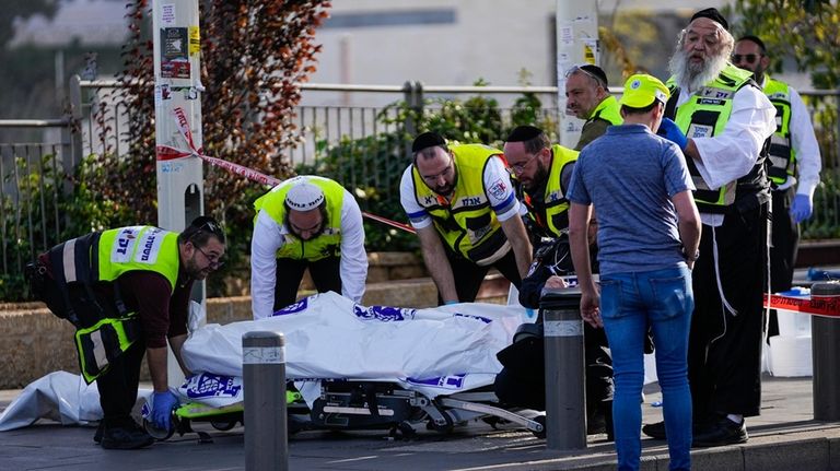 Volunteers from the Zaka rescue service remove a body killed...