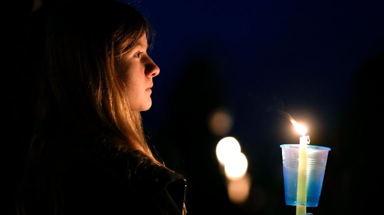 A local resident prays during a candlelight vigil following a...