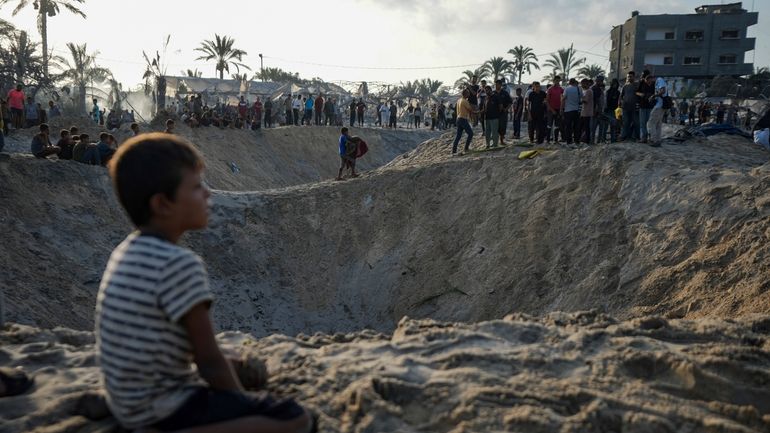 Palestinians look at the destruction after an Israeli airstrike on...