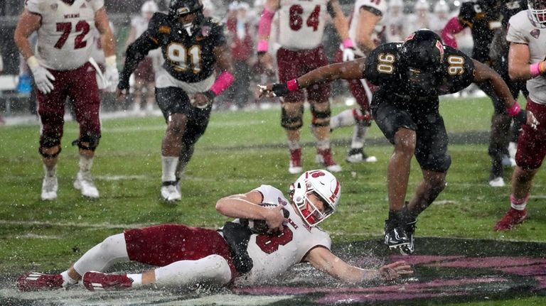 Miami (Ohio) quarterback Maddox Kopp, lower left, slips and falls...