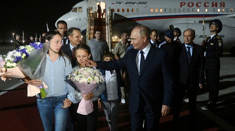 Russian President Vladimir Putin, foreground right, walks with released Russian...