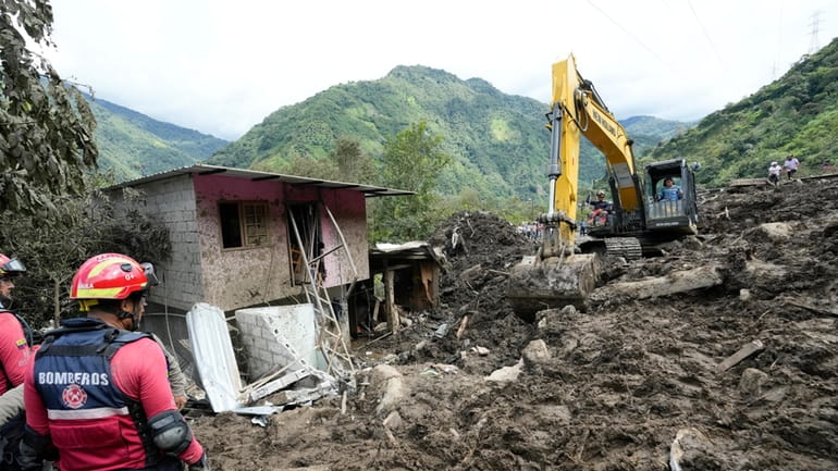 A tractor removes the debris caused by a landslide in...