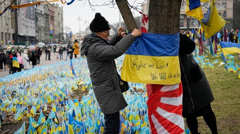 Fuminori Tsuchiko, a 75-year-old Japanese volunteer, ties a Ukrainian flag...