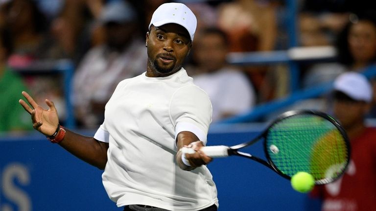 Donald Young, of the United States, returns the ball to...