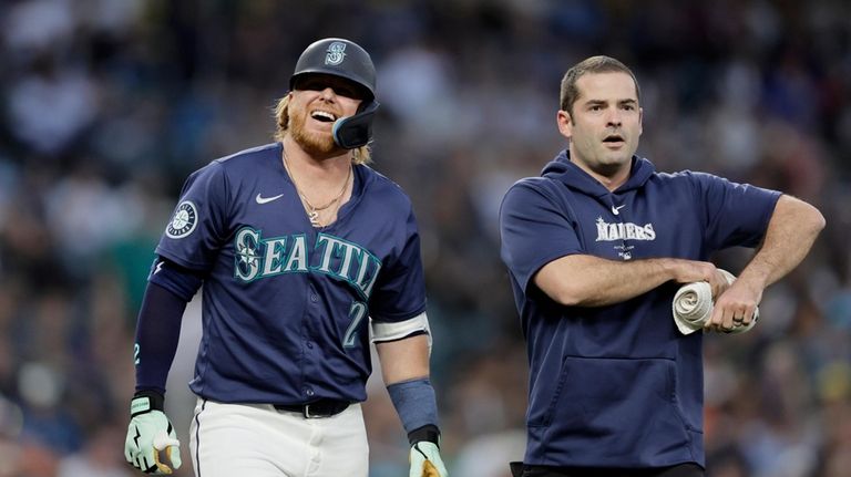 Seattle Mariners' Justin Turner walks with a trainer after he...