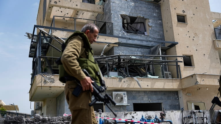 Israeli security forces examine the site hit by a rocket...