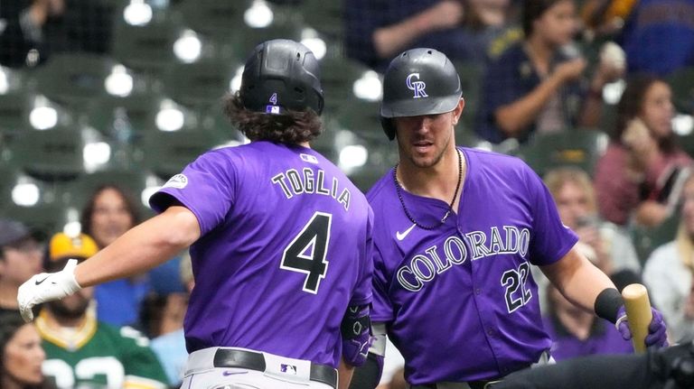 Colorado Rockies' Michael Toglia (4) high-fives Colorado Rockies Nolan Jones...