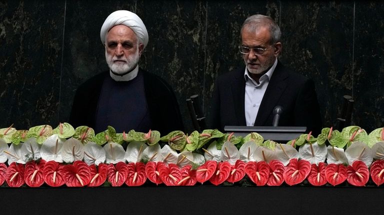 Newly-elected President Masoud Pezeshkian, right, takes his oath, as Judiciary...