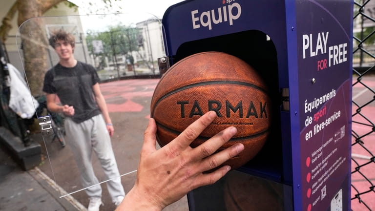 A man puts back a basketball into a free self-service...