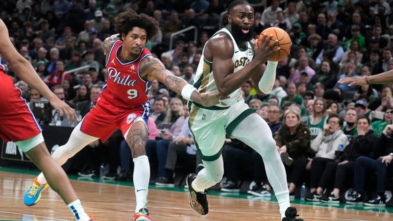 Boston Celtics guard Jaylen Brown, right, drives to the basket...