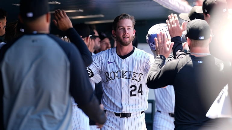 Colorado Rockies' Ryan McMahon is congratulated after hitting a two-run...