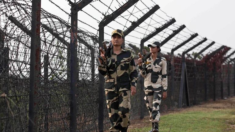 FILE- Indian Border Security Force personnel patrol past a fence...