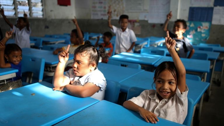 Students raise their hands in class in Dili, East Timor,...