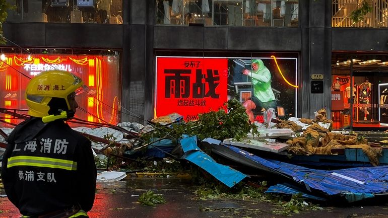 A firefighter stands near debris along a business street in...