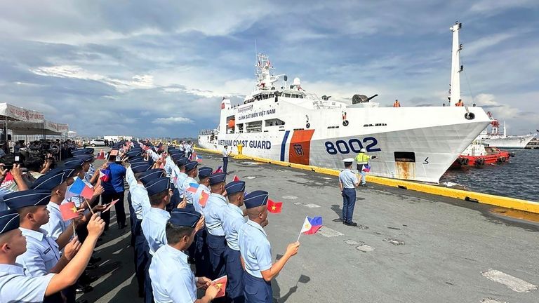 Philippine Coast Guard personnel wave Vietnamese and Filipino flags to...