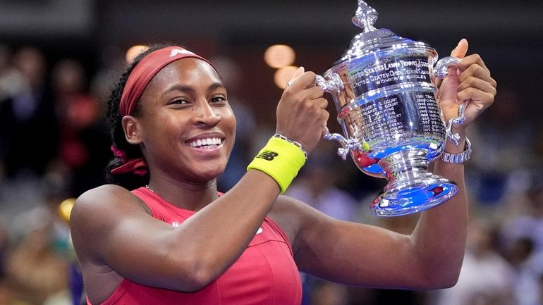 Coco Gauff holds up the championship trophy after defeating Aryna...