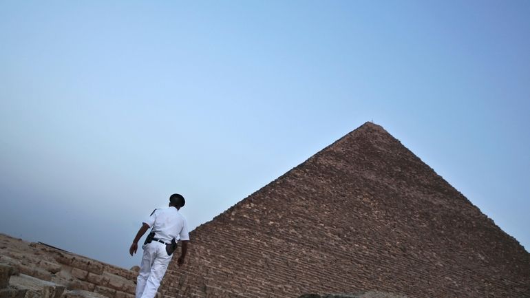 An Egyptian policeman walks near a pyramid in Giza, Egypt,...