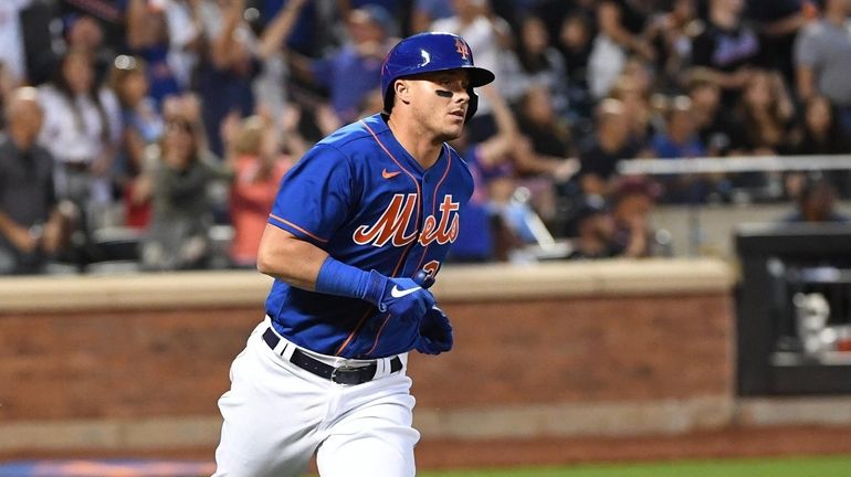 Mets catcher James McCann runs along the first base line...