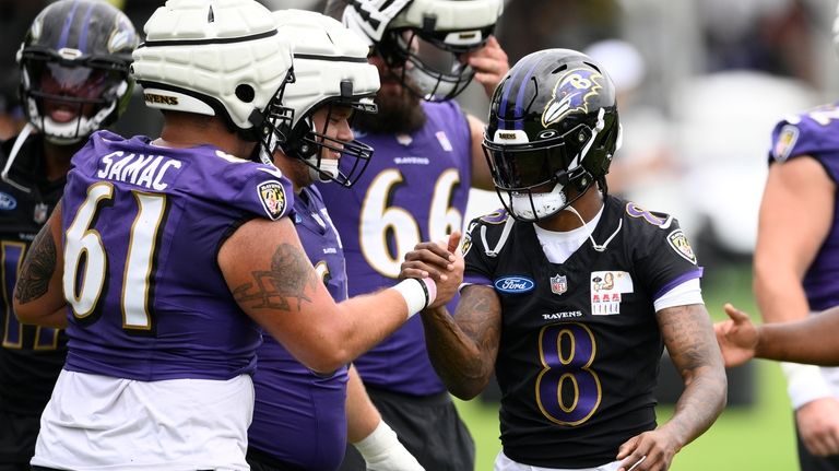 Baltimore Ravens quarterback Lamar Jackson (8) shakes hands with center...