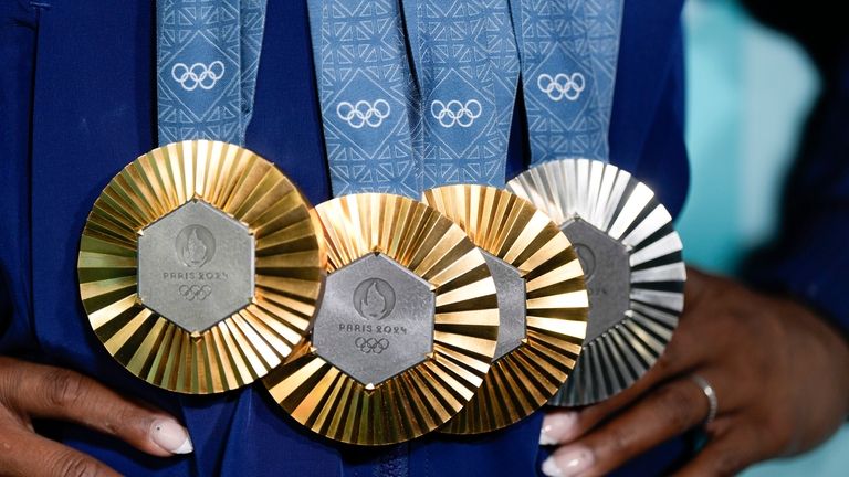 Simone Biles, of the United States, holds up her medals...