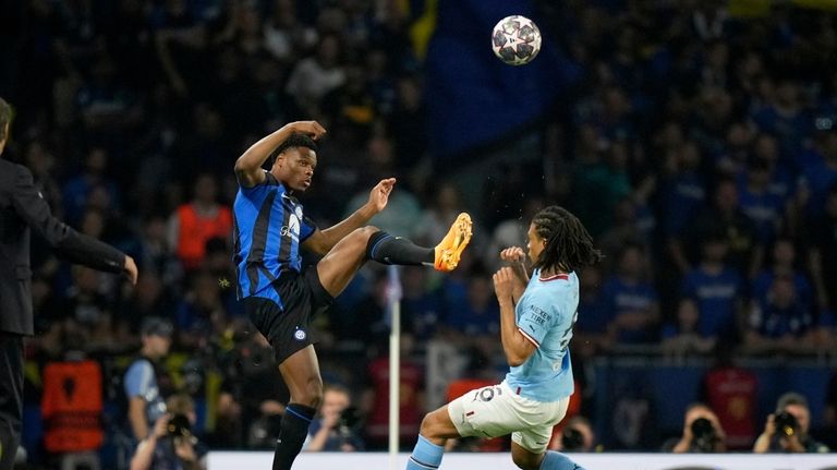 Inter Milan's Denzel Dumfries, left, vies for the ball with...