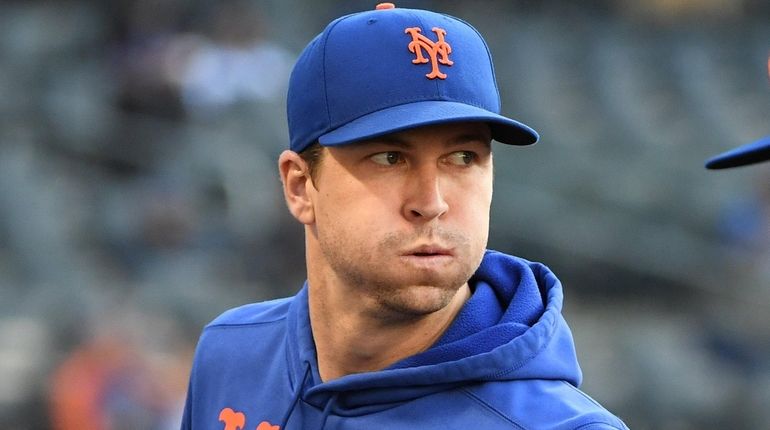 Mets pitcher Jacob deGrom walks to the dugout before game...