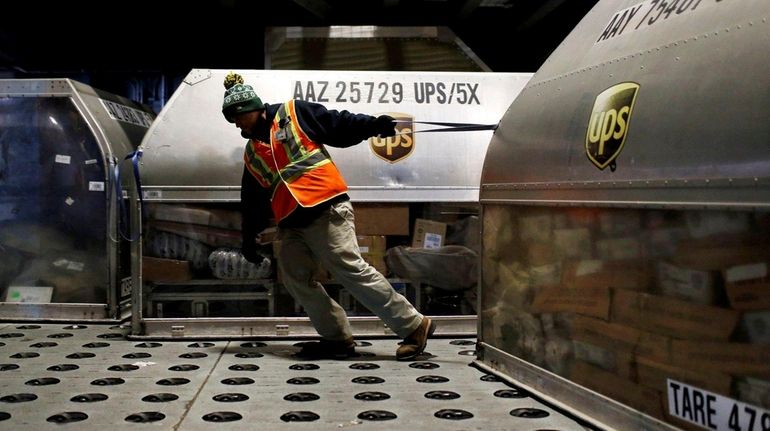 A UPS worker pulls a container full of packages at...