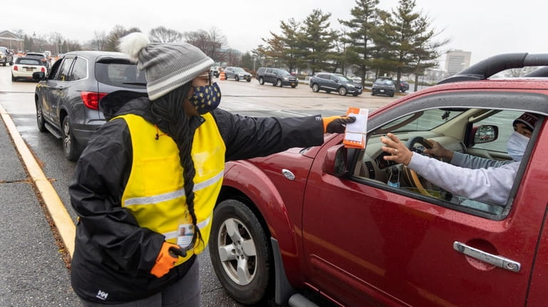 Kimberly Robinson helps hand out COVID-19 testing kits at a drive-up...