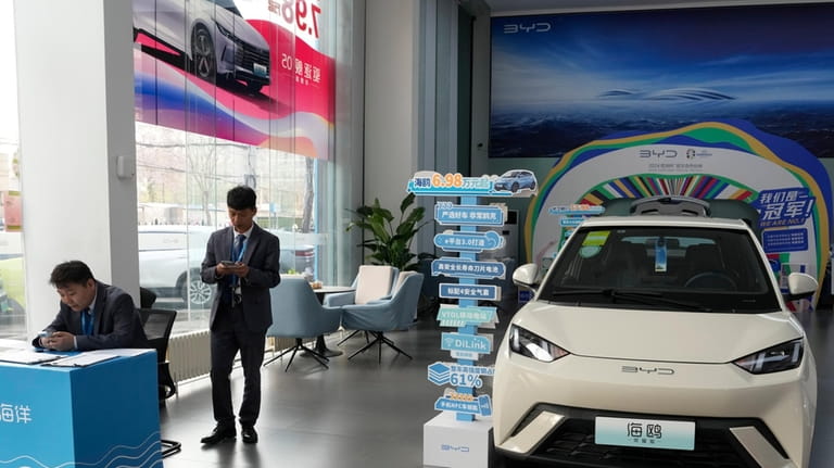 Sales staff stand near the Seagull electric vehicle from Chinese...