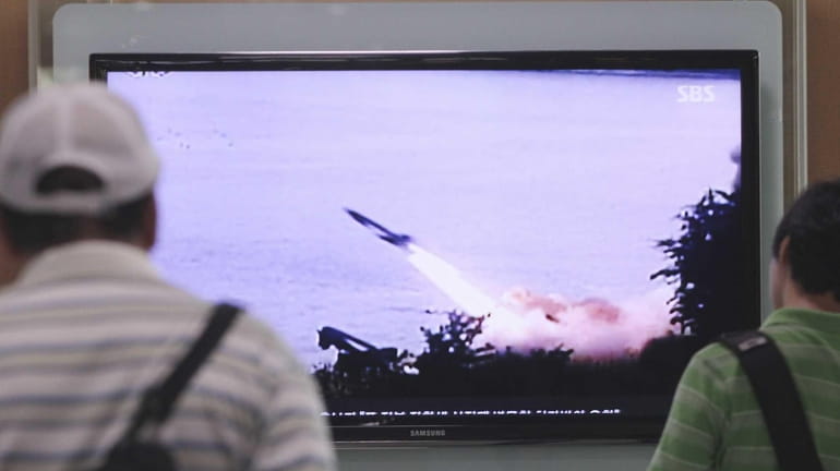 People watch a TV news program showing the missile launch...