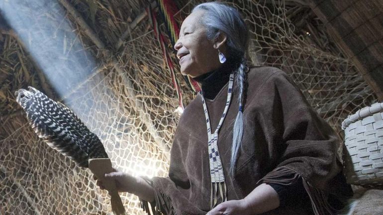 Elizabeth Thunderbird Haile sits upon elk and deer fur while...