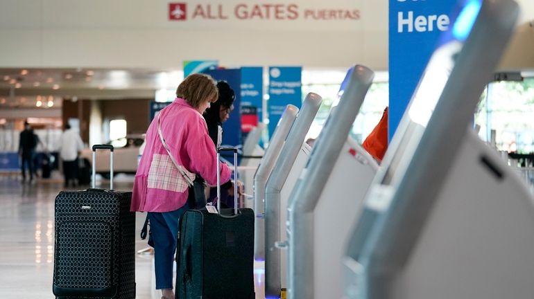 Travelers use the kiosk by the ticketing gate as they...